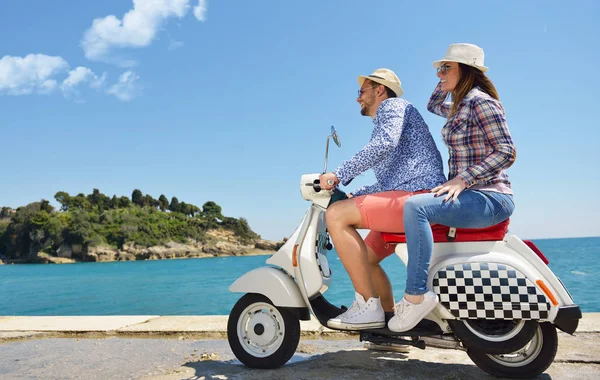 Hermosa pareja joven enamorada disfrutando y divirtiéndose montando en una scooter en una hermosa naturaleza — Foto de Stock