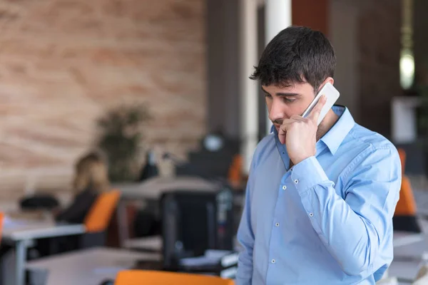 Um homem de negócios jovem e bonito no prédio de escritórios ao telefone — Fotografia de Stock