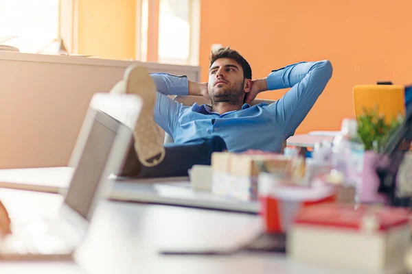 Caucasian business person sitting in office thinking daydreaming hands behind head. — Stock Photo, Image