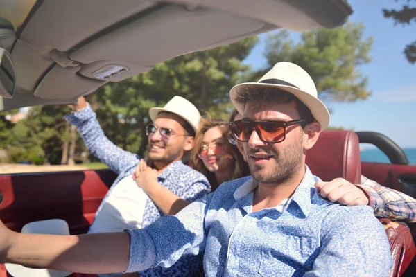 Lazer, viagem rodoviária, viagens e conceito de pessoas - amigos felizes dirigindo em carro cabriolet ao longo da estrada do país — Fotografia de Stock