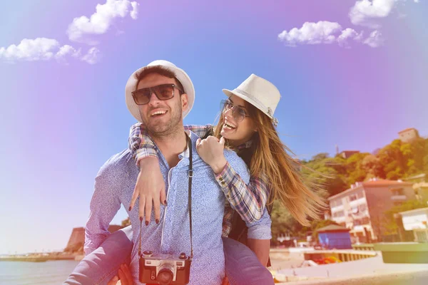 Vista lateral de um casal de 2 turistas com uma mala sentada relaxando e desfrutando de férias em um passeio colorido . — Fotografia de Stock