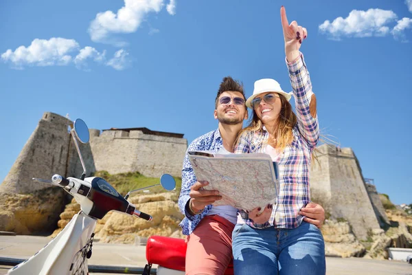 Examinar mapa juntos. Hermosa pareja amorosa joven sentados en scooter juntos y examinar mapa — Foto de Stock