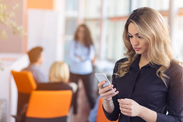 Portrait of young businesswoman in office holding her mobile — Stock Photo, Image