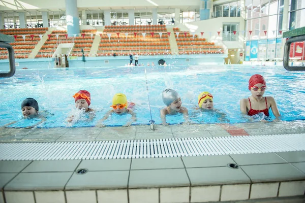 Instruktör och grupp barn göra övningar i närheten av en pool — Stockfoto