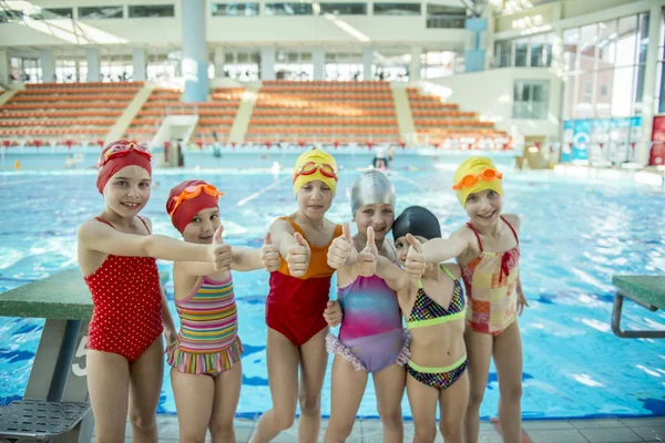 Instruktör och grupp barn göra övningar i närheten av en pool — Stockfoto