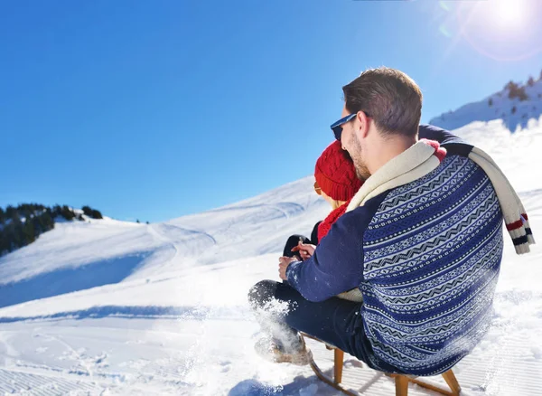 Pareja joven en trineo y disfrutando en el soleado día de invierno — Foto de Stock