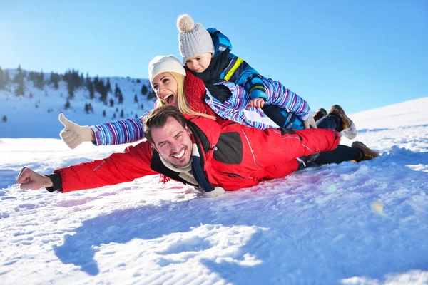 happy young family playing in fresh snow at beautiful sunny winter day outdoor in nature