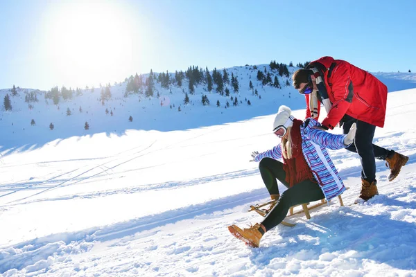 Kızak ve güneşli kış gününde zevk genç Çift