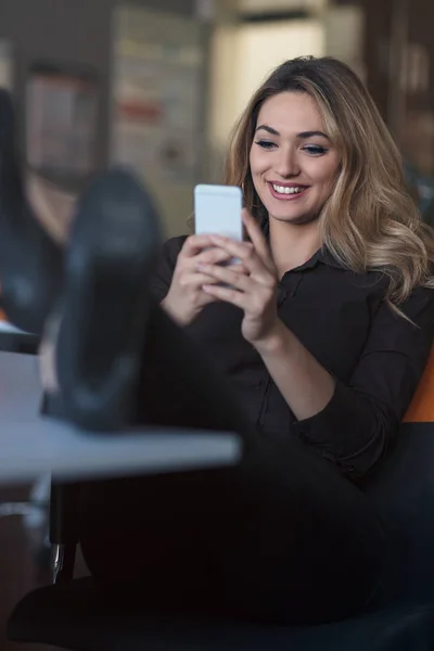 Typing business message. Confident young woman in smart casual wear holding smart phone and looking at it with smile — Stock Photo, Image