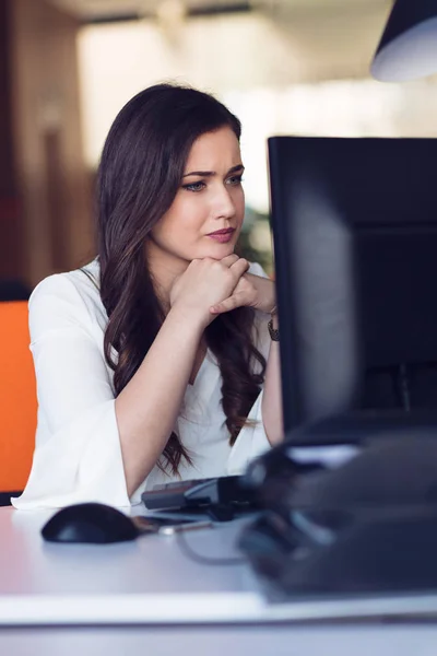 Concentrated middle aged woman working on her computer. Start-up office background