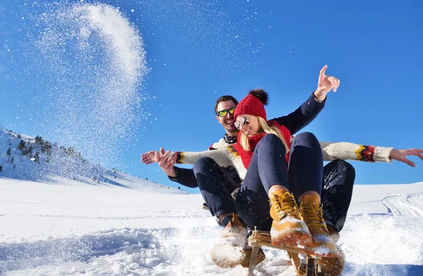 Jong (echt) paar rodelen en genieten op een zonnige winterdag — Stockfoto