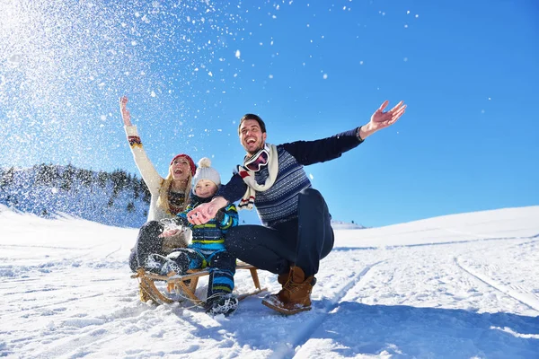 Щаслива молода сім'я грає в свіжому снігу в красивий сонячний зимовий день на відкритому повітрі в природі — стокове фото
