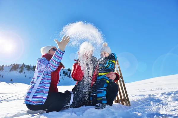Щаслива молода сім'я грає в свіжому снігу в красивий сонячний зимовий день на відкритому повітрі в природі — стокове фото