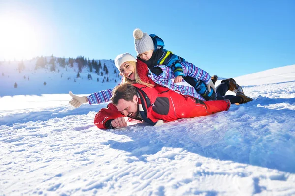 Feliz jovem família jogando na neve fresca no belo dia ensolarado de inverno ao ar livre na natureza — Fotografia de Stock