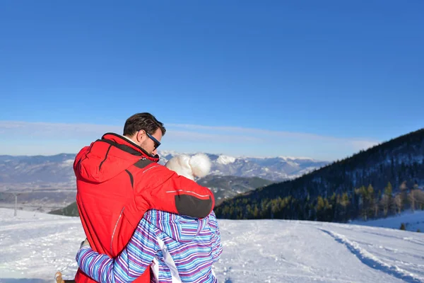 Widok z tyłu miłości para w futra kurtki kaptur patrząc Zasypani górski — Zdjęcie stockowe