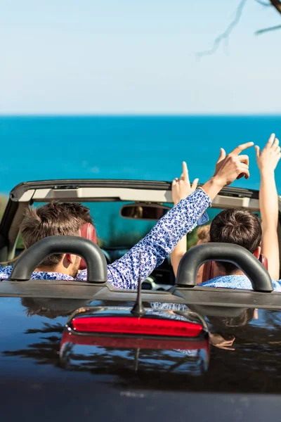 Gruppe fröhlicher junger Freunde im Cabrio mit erhobenen Händen am Sonnenuntergang — Stockfoto