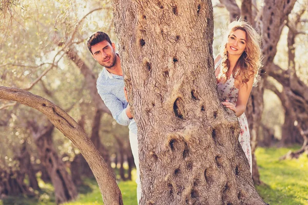 Feliz pareja detrás de gran árbol — Foto de Stock
