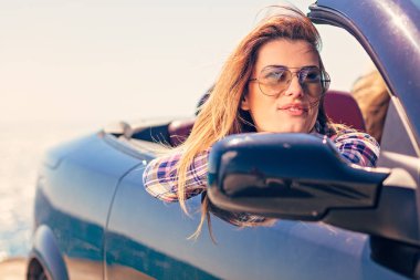 Kapı uzakta deniz özgeçmişlerine bakarak el koyarak Cabriolet oturan kadın önden görünümü.