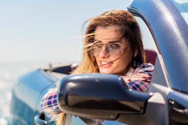 Kapı uzakta deniz özgeçmişlerine bakarak el koyarak Cabriolet oturan kadın önden görünümü.