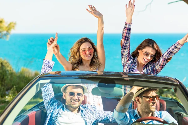 Grupa przyjaciół młodych szczęśliwy w cabriolet z uniesionymi rękoma jazdy na zachód słońca — Zdjęcie stockowe