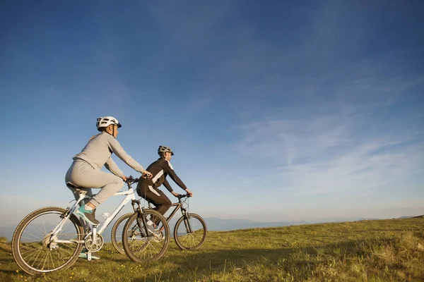 Couple of cyclists on meadow — Stock Photo, Image