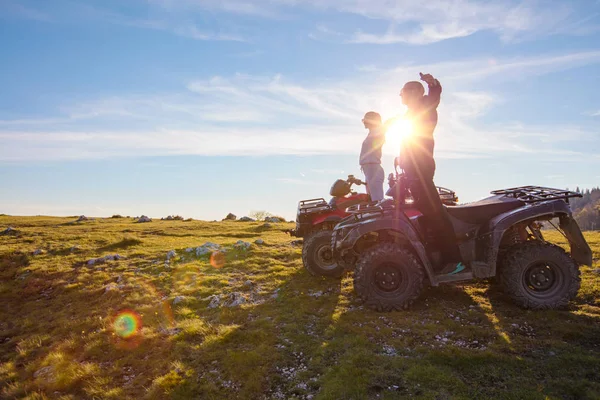 Achteraanzicht van jonge paar in de buurt van atv. Man is iets aan haar vriendin in de afstand tonen. — Stockfoto