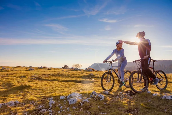 Biker couple with mountain bike pointing in distance at countryside — Stock Photo, Image