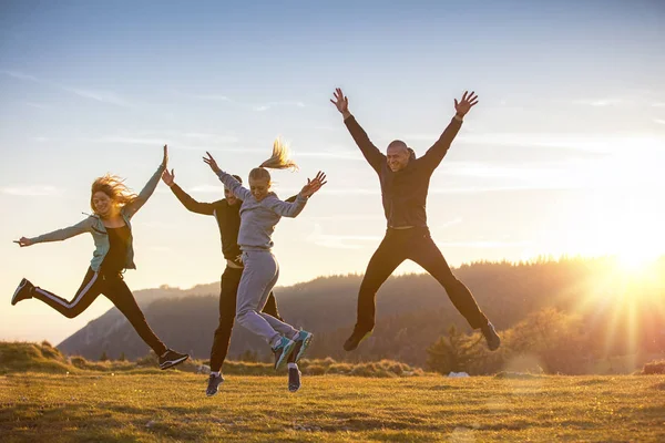 Group of friends running happily together in the grass and jumping — Stock Photo, Image