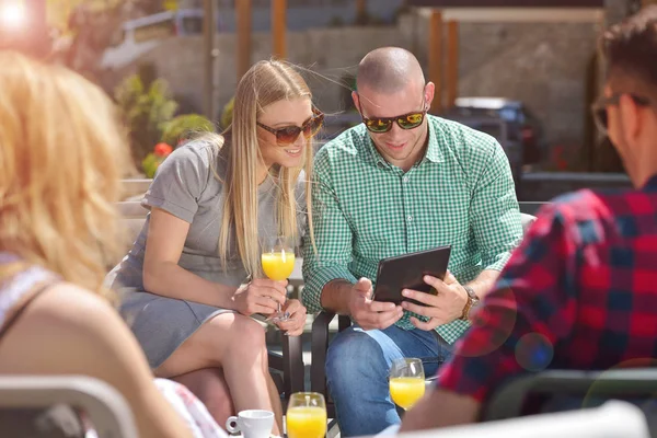 Vacker elegant vänner använder en digital tablett, dricka kaffe och ler medan de vilar i parken — Stockfoto