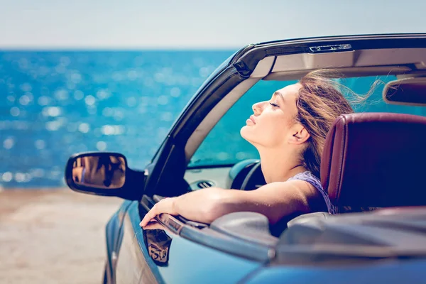 Glückliche und unbeschwerte Frau im Auto am Strand — Stockfoto