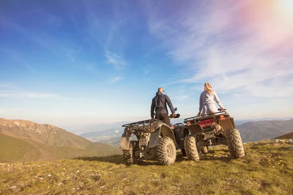 Achteraanzicht van jonge paar in de buurt van atv. Man is iets aan haar vriendin in de afstand tonen. — Stockfoto