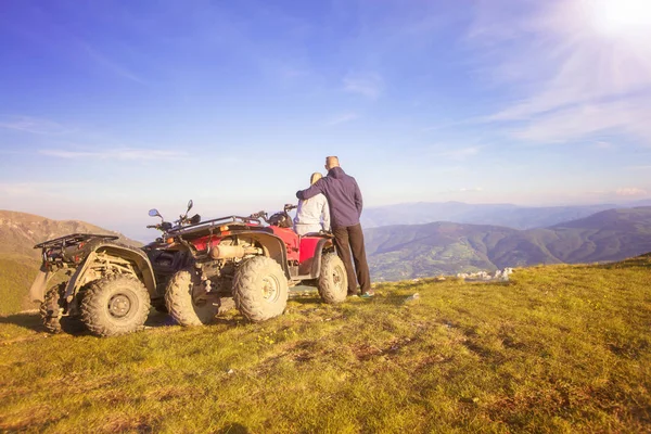 Atv 近く若いペアのリアビュー。男は彼女の恋人の距離で何かを示しています。. — ストック写真