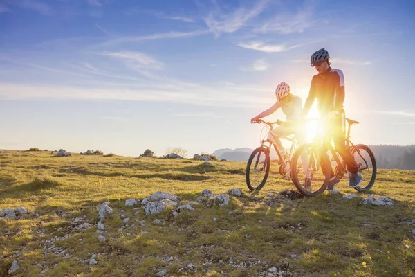 Pareja ciclista con bicicleta de montaña apuntando a la distancia en el campo —  Fotos de Stock