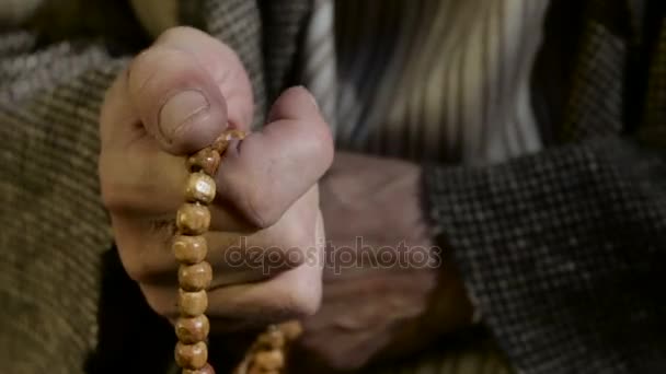 Старик держит в руках молитвенные бусины — стоковое видео