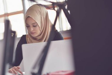 Dizüstü bilgisayar ile ofiste çalışan Müslüman Asyalı kadın