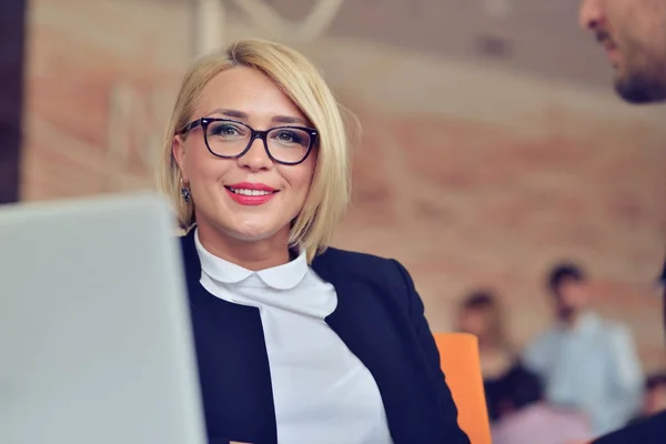 Bella giovane donna che si tiene per mano sul mento e sorride mentre si siede al suo posto di lavoro — Foto Stock