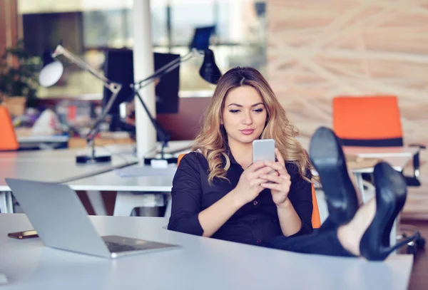 Beautiful young woman is making selfie in her workplace. She is relaxing and putting her legs on the table. — Stock Photo, Image