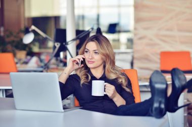 Güzel genç kadın selfie onun işyerinde yapıyor. O rahatlatıcı ve bacaklarını masanın üzerine koyarak.