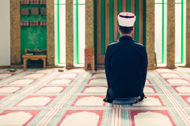 Dindar Müslüman adam caminin içinde dua ediyor.