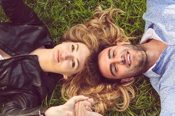 Вид сверху на двух друзей, улыбающихся, глядя в небо, когда они лежат на траве . — стоковое фото