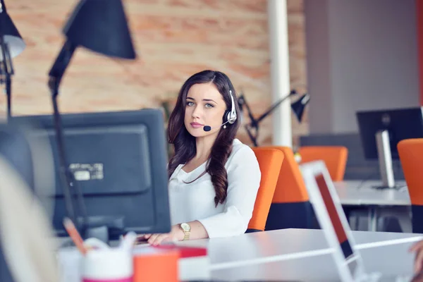 Giovane donna che lavora in call center, circondata da colleghi — Foto Stock