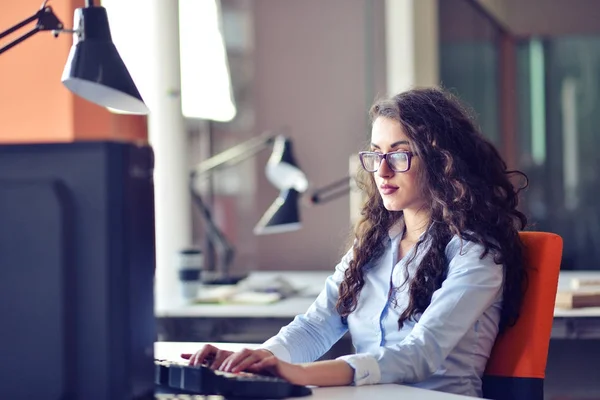 Ritratto di bella giovane donna d'affari sorridente in occhiali seduta sul posto di lavoro — Foto Stock