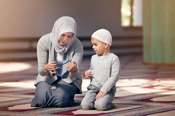 Мусульманская мать учит своего сына молиться в мечети — стоковое фото
