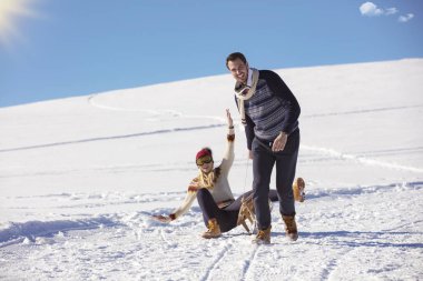Genç oyuncu çift eğleniyor kar sledging kaplı tepe