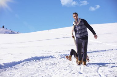 Genç oyuncu çift eğleniyor kar sledging kaplı tepe