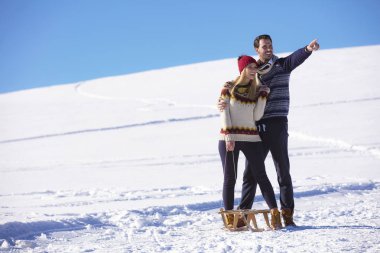 Genç oyuncu çift eğleniyor kar sledging kaplı tepe
