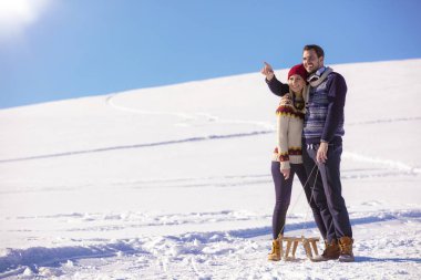 Genç oyuncu çift eğleniyor kar sledging kaplı tepe