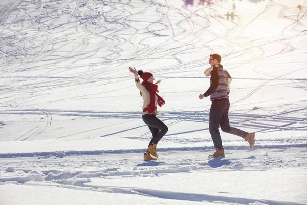 Беззаботная счастливая молодая пара веселится вместе на снегу . — стоковое фото
