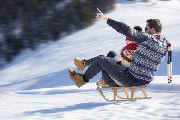 Молодая пара катается на санках и наслаждается солнечным зимним днем — стоковое фото