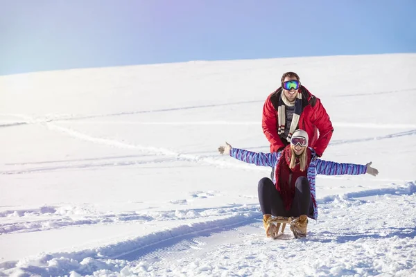 Jovem casal brincalhão se divertindo trenó neve coberto colina — Fotografia de Stock